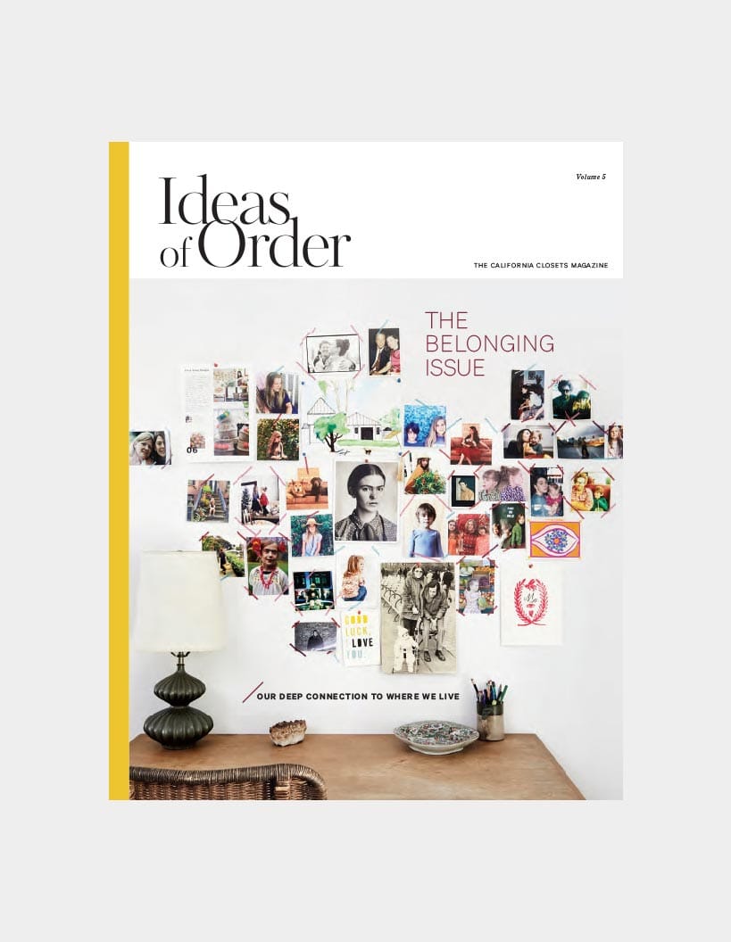 over of Ideas of Order magazine, Volume 5, titled "The Belonging Issue" featuring a collage of various photographs and images pinned on a wall above a wooden desk with a lamp and decorative items
